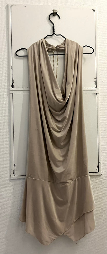Elegant beige backless kjole i strækbar jersey materiale med med åben ryg og draperet halsudskæring – perfekt til festlige anledninger og tidløse looks